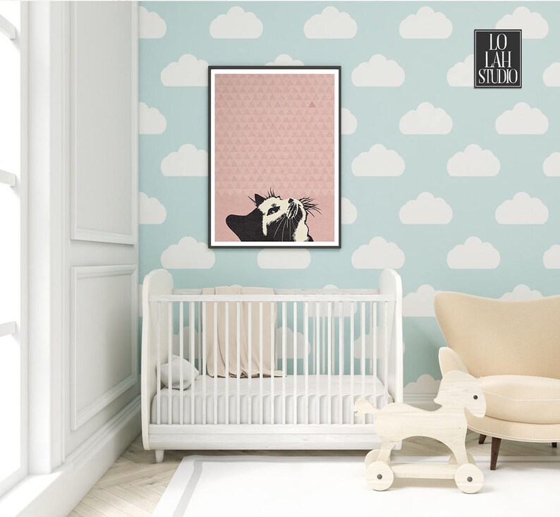 Puede incluir: Un gato blanco y negro mirando hacia arriba a un tri&aacute;ngulo rosa sobre un fondo estampado rosa y blanco. La imagen est&aacute; enmarcada y colgada en una pared azul claro con recortes de nubes blancas. Una cuna blanca y un caballo de balanc&iacute;n de madera est&aacute;n en primer plano.