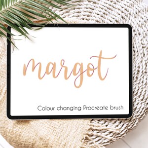 May include: A digital tablet displays the name "margot" in a cursive font, with a color-changing effect. Below the name, the text reads "Colour changing Procreate brush". The tablet rests on a beige woven surface, with a green palm leaf in the upper left corner.