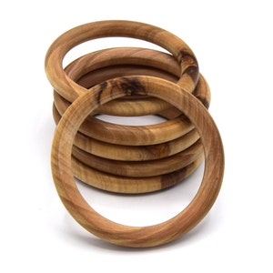 Peut inclure: Six anneaux en bois empilés, chacun avec un motif de grain de bois naturel. Les anneaux sont empilés les uns sur les autres, le plus grand anneau en bas et le plus petit anneau en haut.