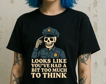 May include: Black t-shirt featuring a skeleton in a police uniform saluting. The skeleton wears a police hat with a star and the shirt has the text "LOOKS LIKE YOU'VE HAD A BIT TOO MUCH TO THINK" in a bold, white font. The design is a humorous take on law enforcement.