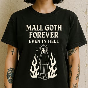 Puede incluir: Camiseta negra con texto blanco que dice "Mall Goth Forever Even in Hell". La camiseta presenta una ilustración de dibujos animados de una persona con cabello negro y una sudadera con capucha negra de pie frente a las llamas.