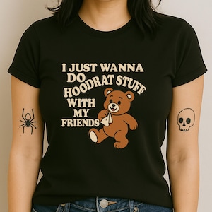 Puede incluir: Camiseta negra con el texto "I JUST WANNA DO HOODRAT STUFF WITH MY FRIENDS" y un gráfico de oso de peluche marrón. La camiseta tiene cuello redondo y mangas cortas.