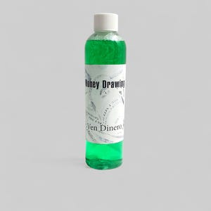 May include: A clear bottle with a white cap filled with bright green liquid. The label reads "Money Drawing" and "Ven Dinero" in black text. The label has a dollar bill design.