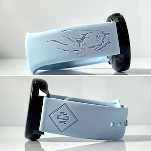 Pode incluir: Uma pulseira de relógio de silicone azul claro com um design de cabeça de cavalo e as letras "ACB" em forma de diamante.