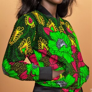 Puede incluir: Una chaqueta bomber negra con estampado floral verde, amarillo y rosa. La chaqueta tiene cierre de cremallera y cuello, pu&ntilde;os y cintura de canal&eacute;.