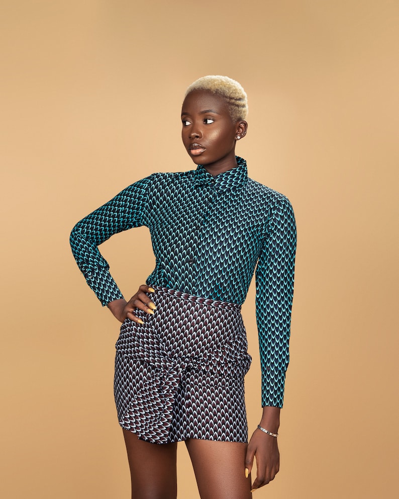 K&ouml;nnte beinhalten: Eine Person tr&auml;gt ein blau-schwarz gemustertes Hemd und einen schwarz-wei&szlig; gemusterten Rock. Die Person hat kurze blonde Haare.