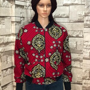 Puede incluir: Una chaqueta bomber roja con estampado floral negro y dorado. La chaqueta tiene cierre de cremallera y pu&ntilde;os y cintura de canal&eacute;.
