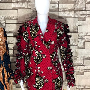 May include: A red dress with a black and gold floral pattern. The dress has a V-neckline and long sleeves with ruffles.