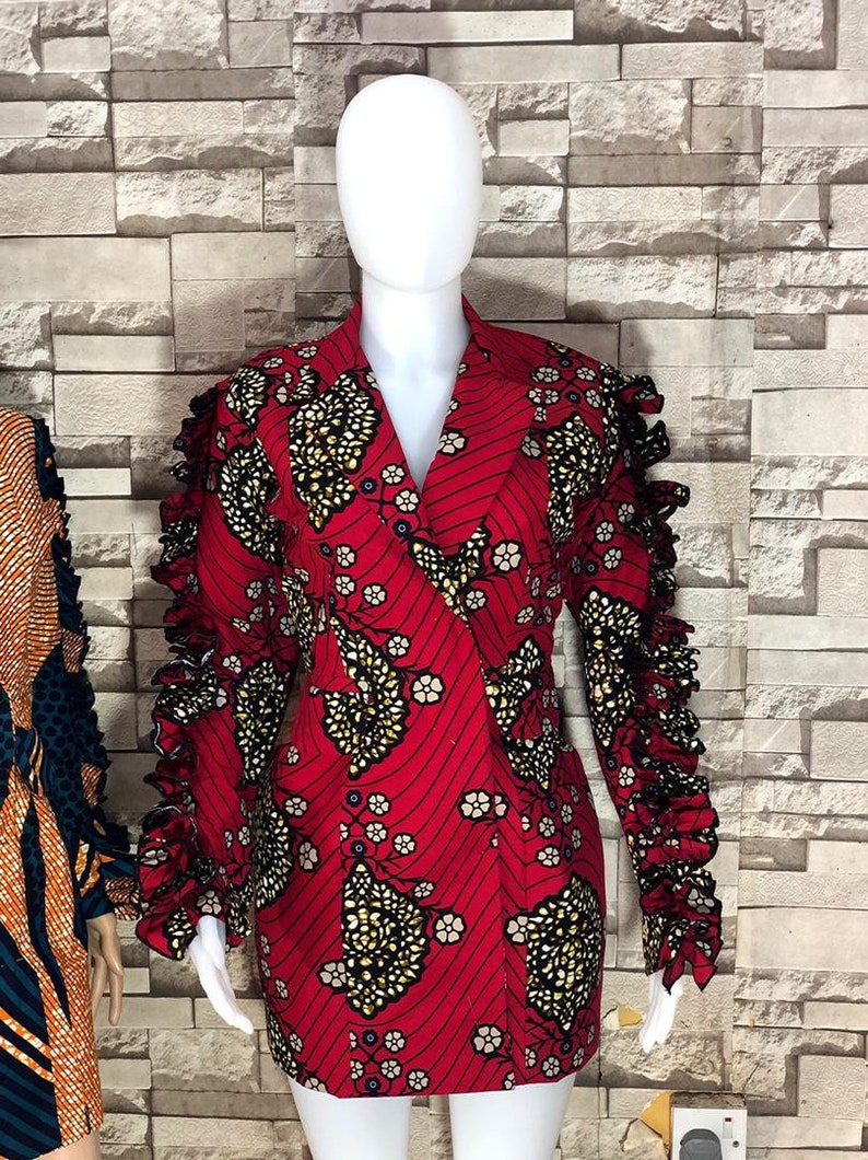 May include: A red dress with a black and gold floral pattern. The dress has a V-neckline and long sleeves with ruffles.