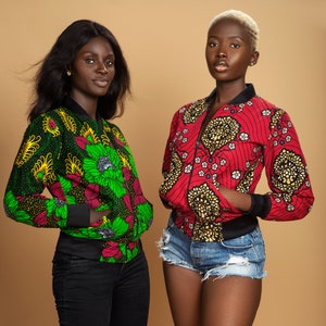 Puede incluir: Dos mujeres con chaquetas bomber de estampado colorido. Una mujer lleva una chaqueta verde y negra y la otra una chaqueta roja y negra. Ambas mujeres llevan pantalones negros y tienen la piel oscura.