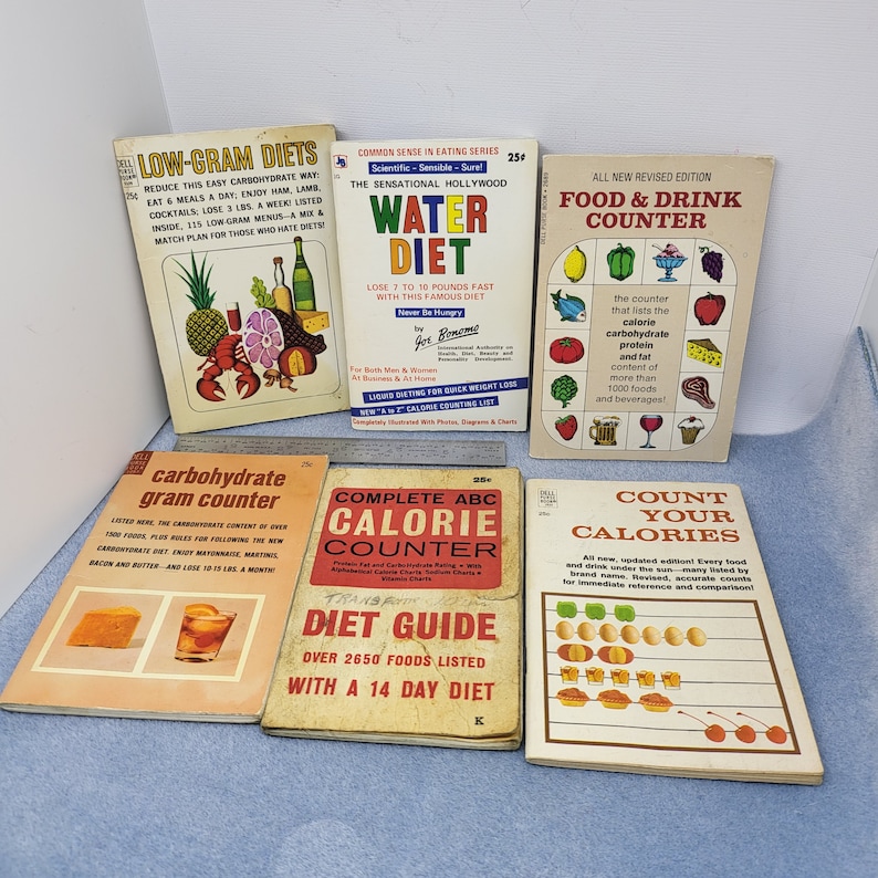 May include: A collection of vintage diet books with colorful covers. Titles include "Low-Gram Diets," "Water Diet," "Food & Drink Counter," "Carbohydrate Gram Counter," "Complete ABC Calorie Counter," and "Count Your Calories."