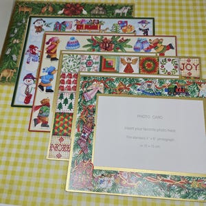 May include: A set of layered Christmas-themed paper photo frames with festive illustrations including snowmen, bears, and holiday greenery. The top frame features the text 'PHOTO CARD' and 'Fits standard 4" x 6" photograph or 10 x 15 cm'.