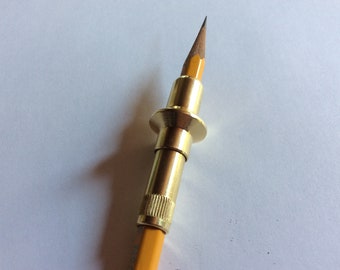 May include: A gold-colored pencil extender with a brass ring and a yellow pencil inserted.
