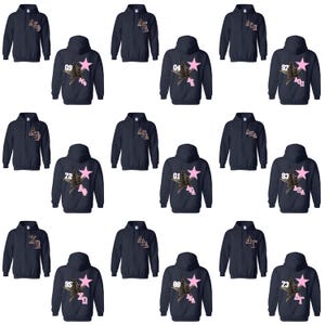 May include: Navy blue hooded sweatshirts with various designs. Some sweatshirts feature a pink star with a leopard print design and a number. Other sweatshirts have text on the front.