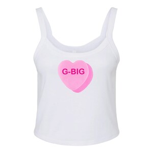 K&ouml;nnte beinhalten: Wei&szlig;es Tanktop mit einem rosafarbenen herzf&ouml;rmigen Bonbon mit dem Text "G-BIG" in rosa Buchstaben.