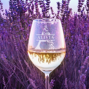 May include: A clear wine glass with the name "Allivia" etched into the side, surrounded by a field of purple lavender flowers.