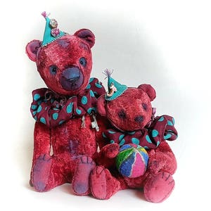 May include: Two plush teddy bears wearing colorful hats and a polka dot collar. The larger bear is holding a key. The smaller bear is holding a colorful ball.