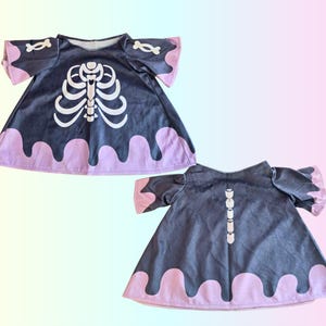 May include: A dark gray dress with a white skeleton design on the front and back. The dress has short sleeves with bone accents and a pink trim along the bottom and sleeves. The dress is a costume.