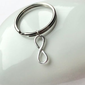 May include: Silver infinity symbol keyring. The infinity symbol is attached to a silver key ring.