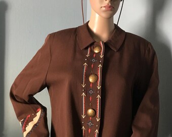 May include: A brown jacket with embroidered details in red, white, and blue. The jacket has a button-up front and long sleeves. The sleeves have a geometric pattern on the cuffs.
