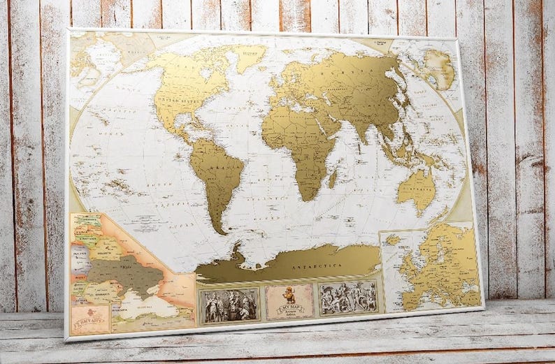 Peut inclure: Une carte du monde &agrave; gratter rectangulaire pr&eacute;sentant des continents de couleur dor&eacute;e sur un fond blanc. La carte comprend des &eacute;tiquettes g&eacute;ographiques d&eacute;taill&eacute;es, une carte encart de l'Europe et trois illustrations d&eacute;coratives en bas.
