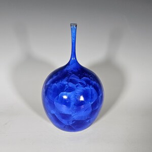 May include: A cobalt blue ceramic vase with a round body and a long, thin neck.