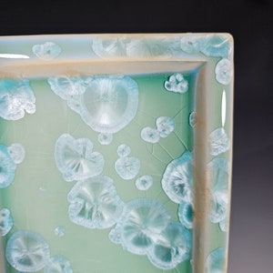 Puede incluir: Una bandeja rectangular de cer&aacute;mica con un esmalte verde claro y un patr&oacute;n de c&iacute;rculos blancos en relieve.