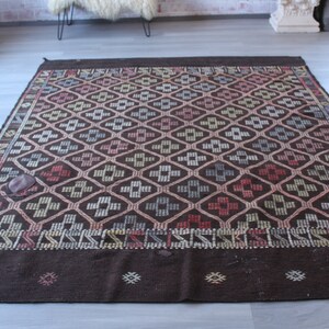 May include: A brown and white geometric patterned rug with a dark brown border. The rug has a traditional design with repeating diamond shapes.
