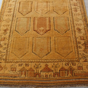 May include: A traditional Turkish rug with a geometric pattern in shades of brown and beige. The rug has a fringe border and is made of wool.