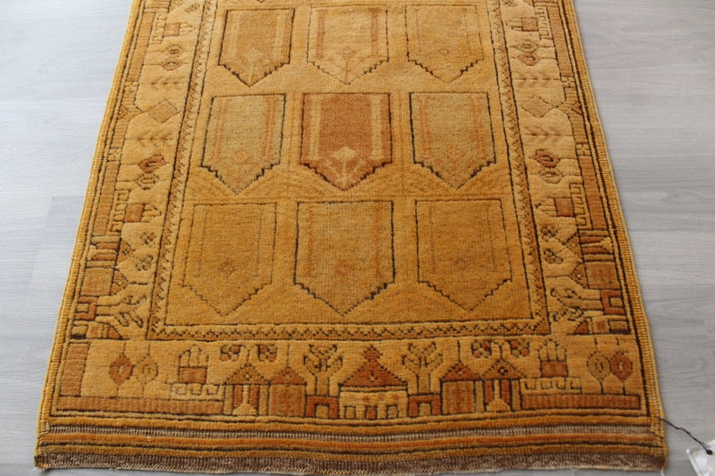 May include: A traditional Turkish rug with a geometric pattern in shades of brown and beige. The rug has a fringe border and is made of wool.