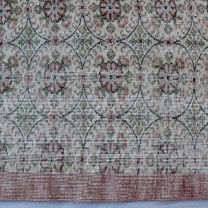 May include: A vintage rug with a floral pattern in shades of pink, green, and white. The rug has a distressed look and a fringe border.