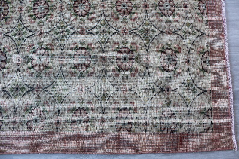 May include: A vintage rug with a floral pattern in shades of pink, green, and white. The rug has a distressed look and a fringe border.