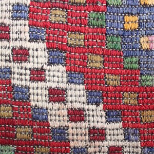 Op de afbeelding: Close-up van een kleurrijk geweven stof met een geometrisch patroon. De stof is gemaakt van draden in verschillende kleuren, waaronder rood, blauw, groen en geel.