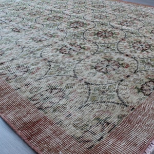 May include: A vintage rug with a floral pattern in shades of pink, green, and white. The rug has a fringed edge and a worn, distressed look.