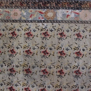 May include: A vintage rug with a beige background and a repeating pattern of small, stylized flowers in shades of red, black, and yellow. The rug has a border with a floral design in shades of pink, blue, and white.