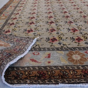 May include: A vintage rug with a floral pattern in shades of beige, brown, and red. The rug has a fringe border and is in good condition.