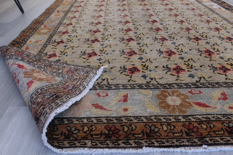 May include: A vintage rug with a floral pattern in shades of beige, brown, and red. The rug has a fringe border and is in good condition.