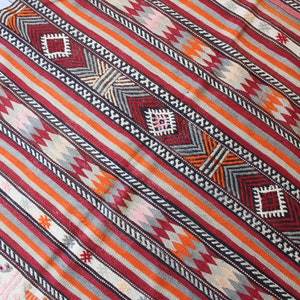 May include: A colorful striped rug with geometric patterns in shades of red, orange, gray, white, and black.