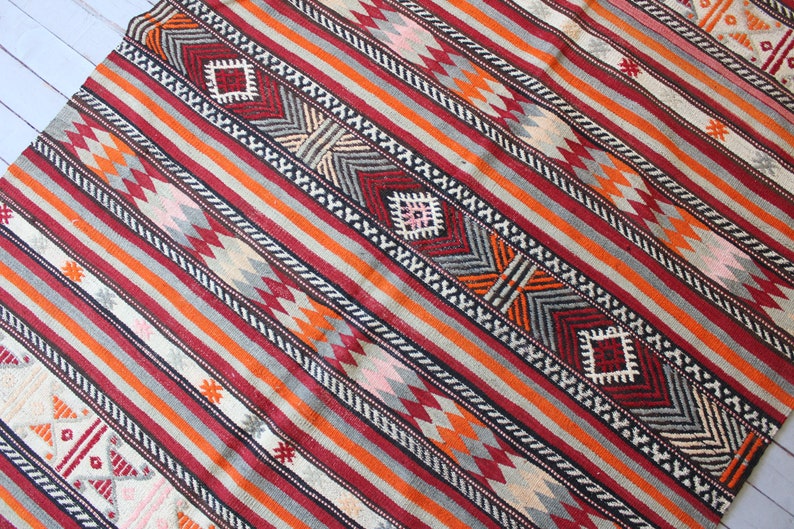 May include: A colorful striped rug with geometric patterns in shades of red, orange, gray, white, and black.