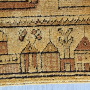 May include: Close-up of a beige rug with a brown border. The rug has a repeating pattern of stylized houses and trees.