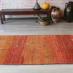 May include: A rectangular orange and red area rug with a subtle pattern. The rug has a woven texture and is made of natural fibers.