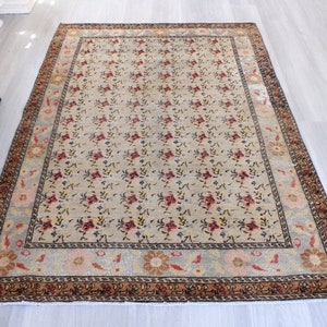 May include: A vintage floral patterned rug with a cream background and a brown, red, and blue border. The rug has a faded look and is in good condition.