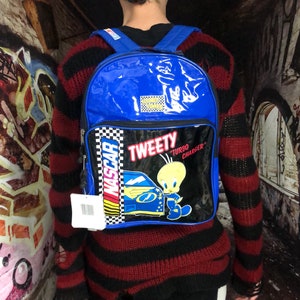 May include: Blue and black backpack featuring a Tweety Bird design. The backpack has a chequered pattern and the words "Tweety" and "Turbo Charger" on it.