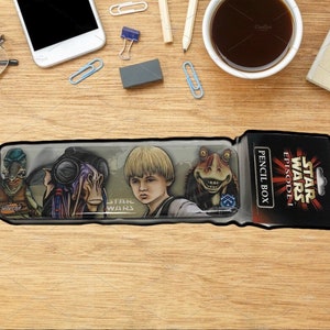 Puede incluir: Un estuche de lápices de Star Wars Episodio I con ilustraciones de personajes. El estuche tiene una parte delantera de plástico transparente con imágenes de personajes de la película. El embalaje incluye el logotipo de Star Wars y las palabras "Pencil Box".