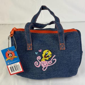 May include: Denim handbag with Tweety Bird embroidery and the word "Sassy". The bag has orange trim and handles, a matching zip, and a Looney Tunes tag.