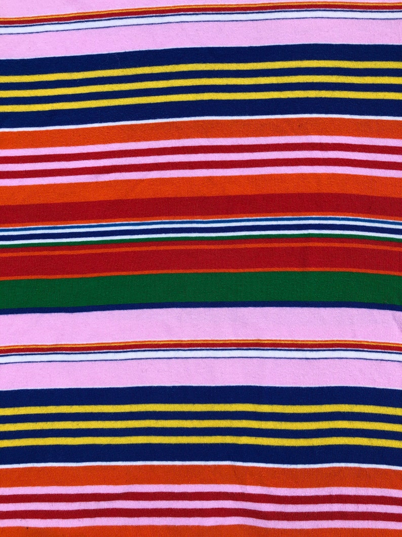 Peut inclure: Un tissu ray&eacute; avec des bandes altern&eacute;es de rose, rouge, orange, jaune, vert, bleu et blanc.