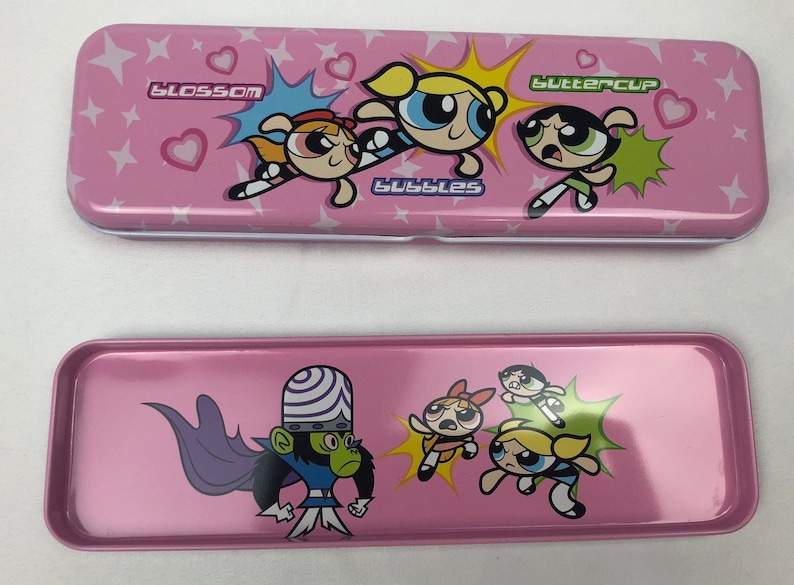 May include: Pink metal pencil case featuring the Powerpuff Girls, Blossom, Bubbles, and Buttercup. The case has a white interior and a separate compartment for storing pencils and other supplies. The case also features the Powerpuff Girls' arch-nemesis, Mojo Jojo.