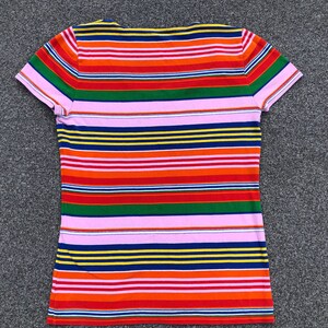 Peut inclure: Un t-shirt &agrave; manches courtes ray&eacute; avec un col en V. Le t-shirt a des rayures altern&eacute;es de rose, rouge, orange, jaune, vert, bleu et marine.