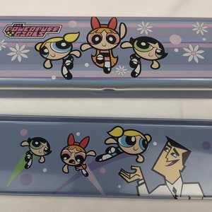 May include: A purple and blue metal pencil case with a graphic of the Powerpuff Girls. The case is closed and the top has the words "The Powerpuff Girls" printed on it. The bottom of the case has a graphic of the Powerpuff Girls and Professor Utonium.
