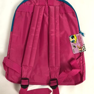 May include: Pink backpack with blue trim and adjustable straps. The backpack has a zippered pocket on the front and a tag with the words "Powerpuff Girls" on the side.